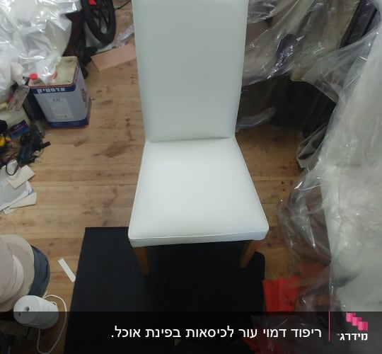 כיסא מרופד בלבן עם רגלי עץ על רצפת עץ
